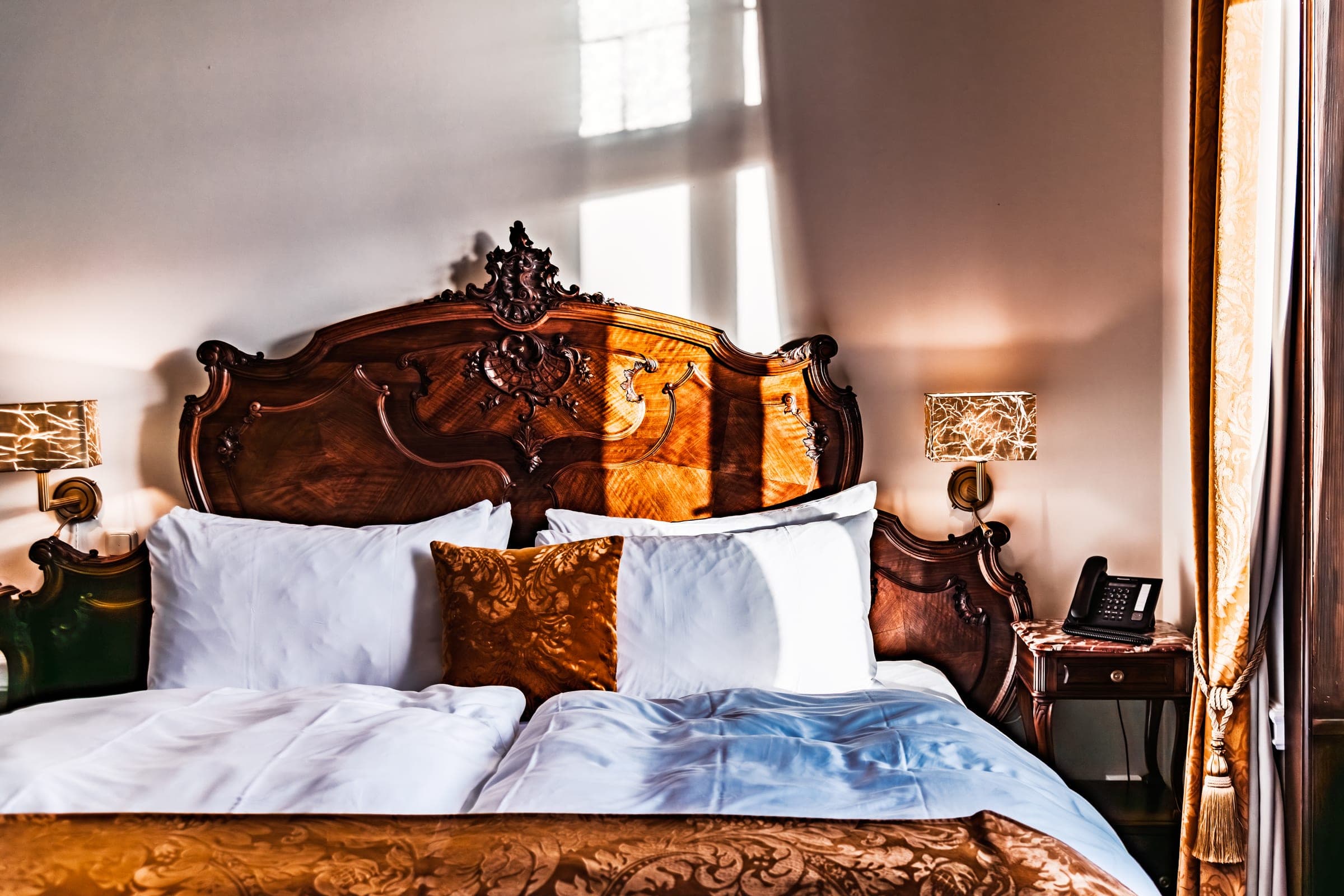 Ornate carved bed in sunlit hotel room